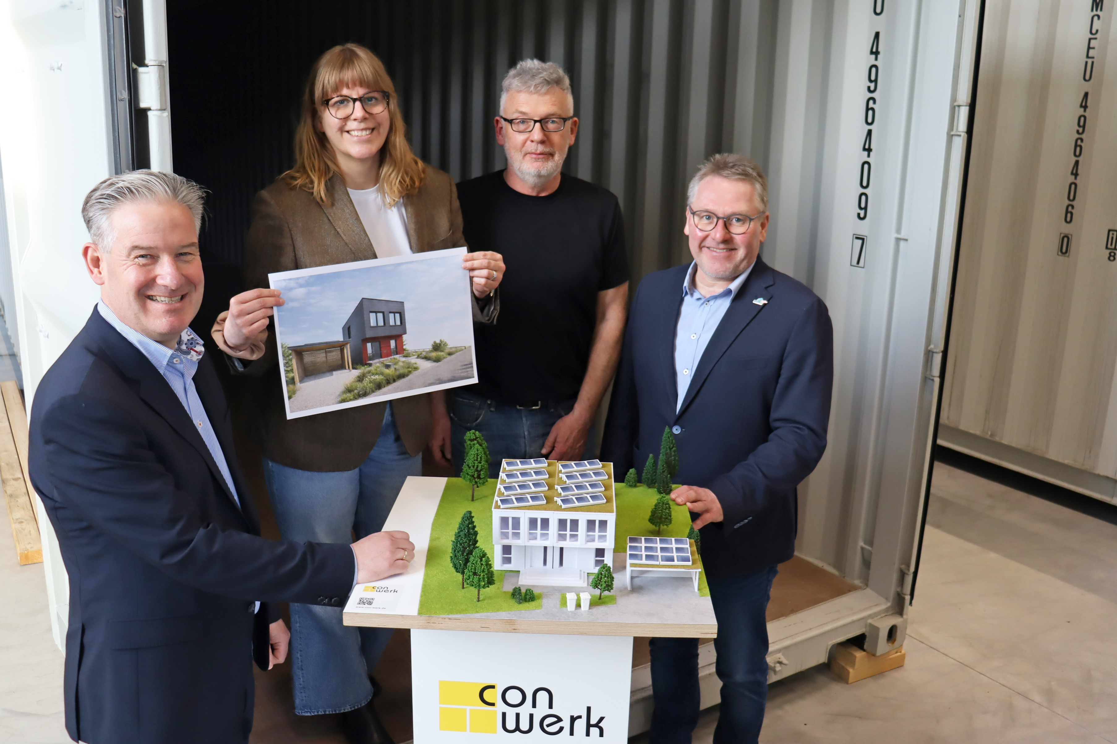 Vom Transportcontainer zum Wohnhaus (v. l.): B�rgermeister Michael Berens, die conwerk-Unternehmensleitung Ramona Schr�r und Harald B�rhold sowie Wirtschaftsf�rderer Thomas Westhof mit einem Modell der modularen H�user und einer Visualisierung des geplant